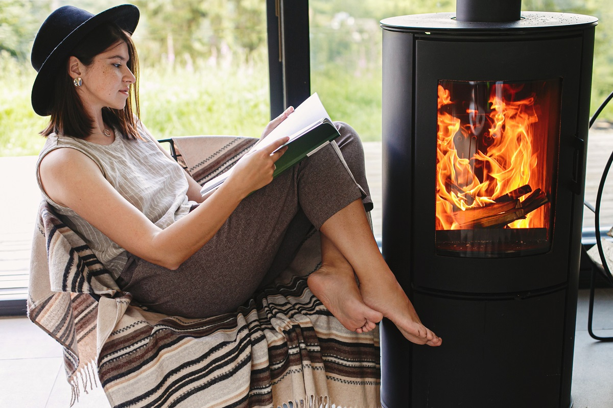 kominek piec komin książka kapelusz stopy fotel koc dziewczyna kobieta czytelnictwo