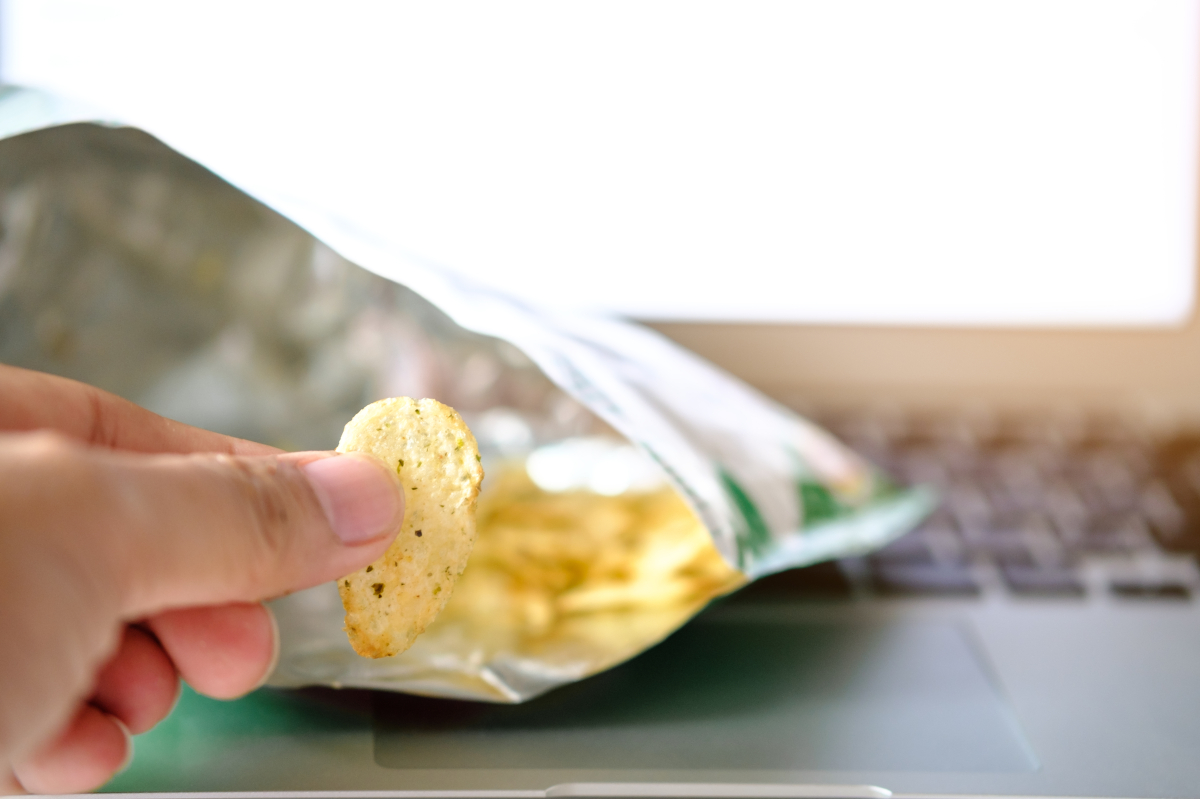 Finger,Hand,With,Potato,Chips,(empty),On,Notebook,Background