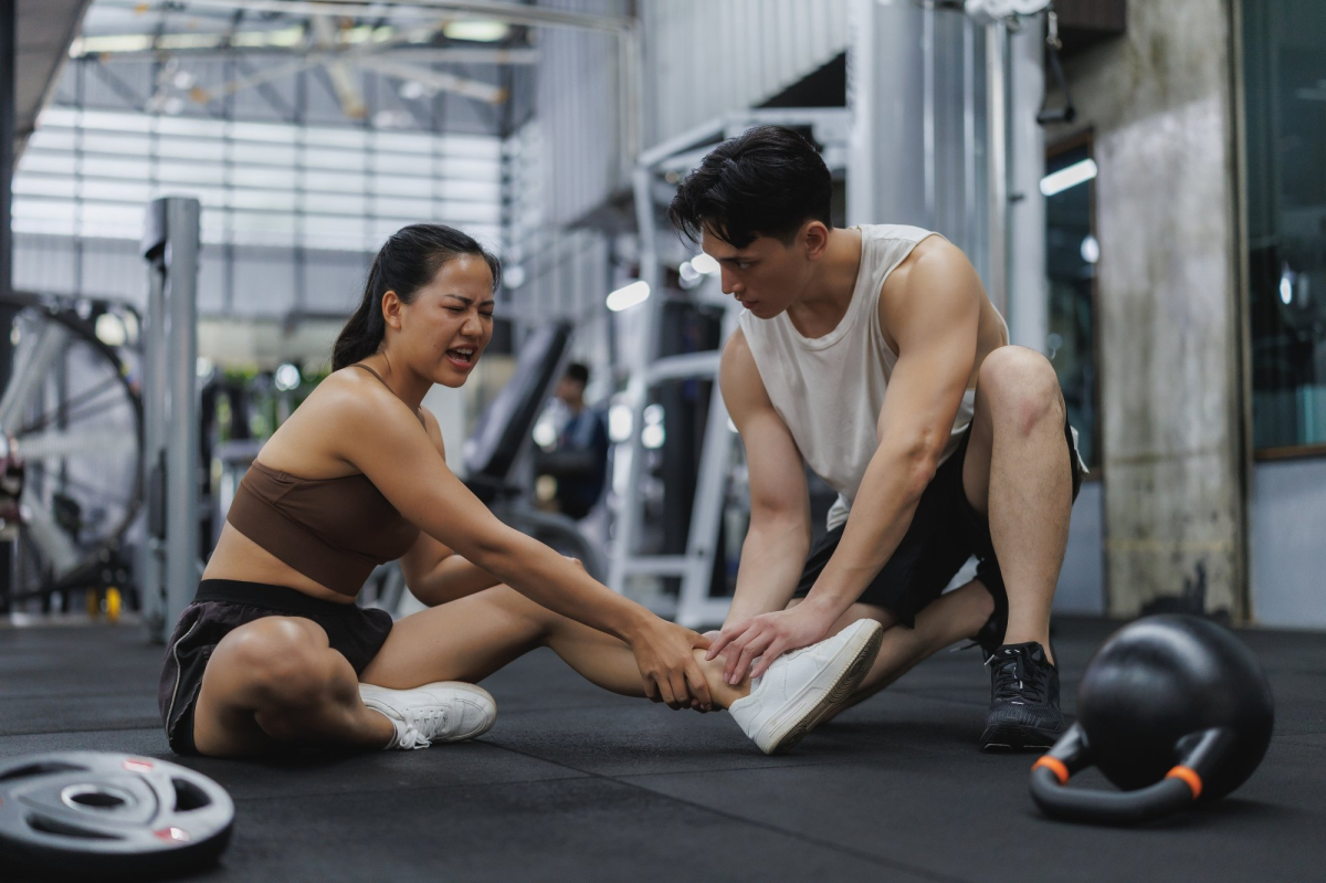 Young,Woman,Experiencing,Ankle,Pain,During,Workout,At,Gym,,Receiving