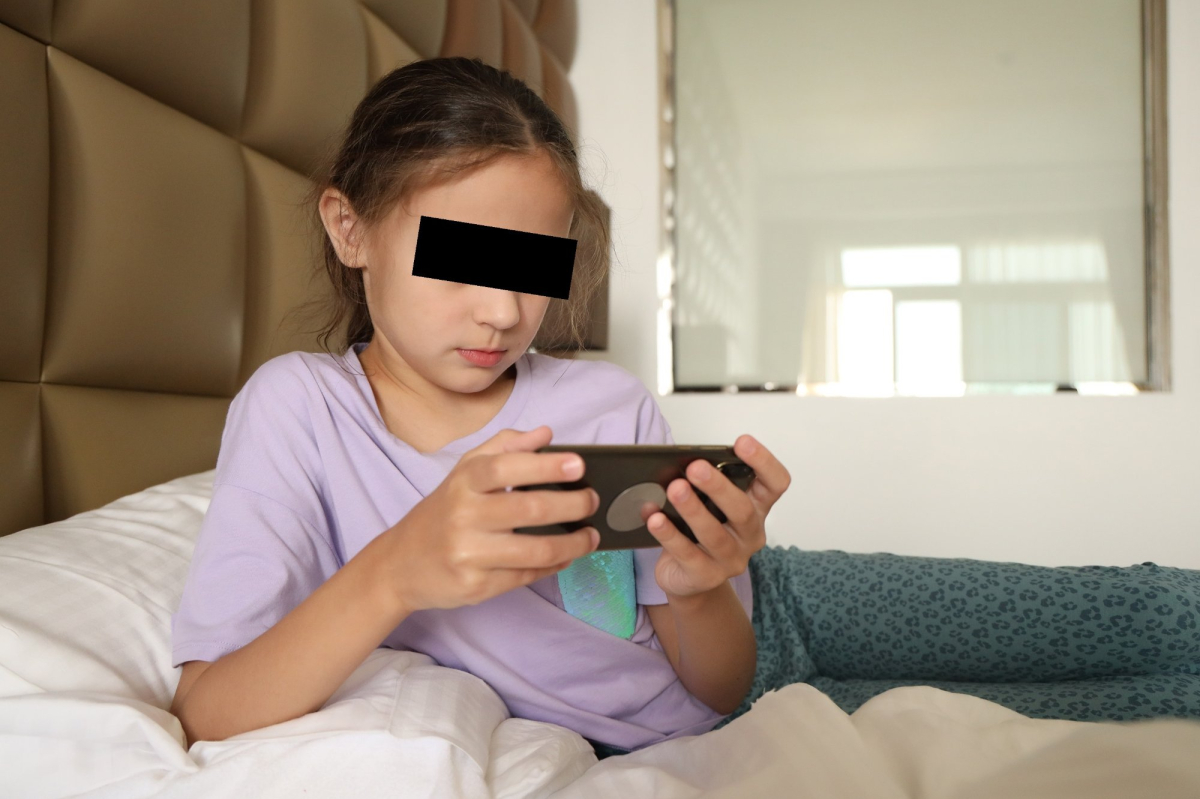 uczennica zakryte oczy trzyma w ręku telefon