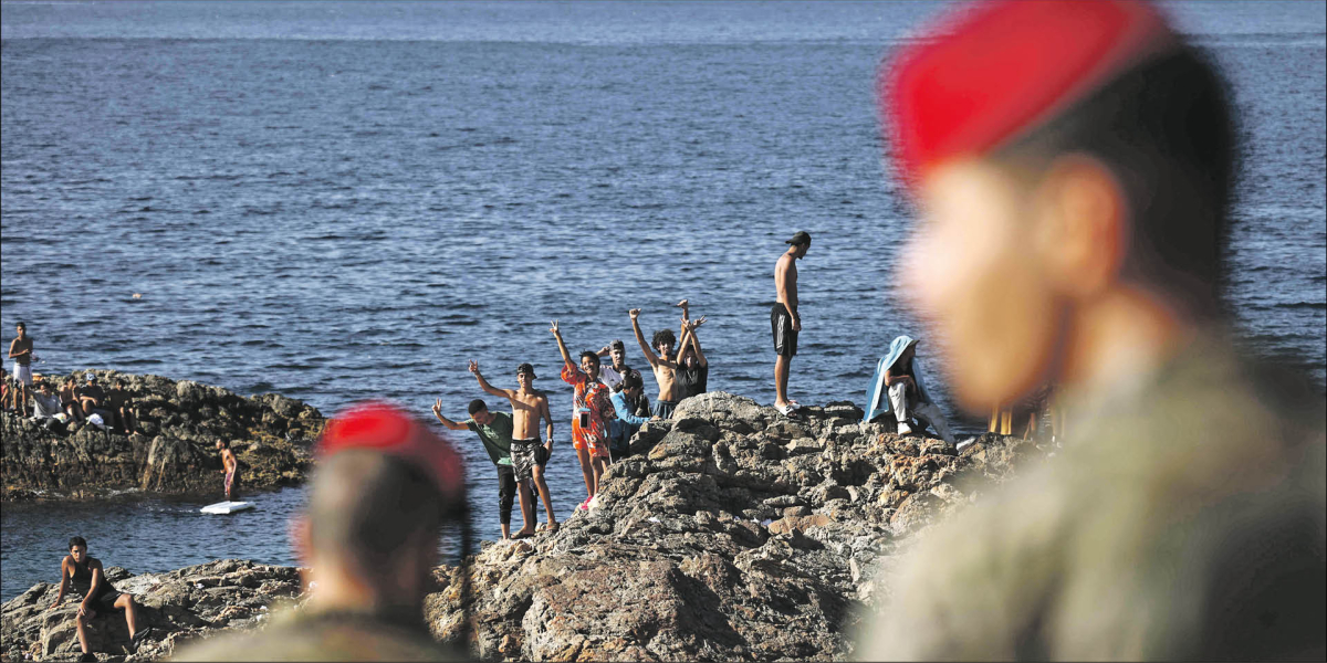 Hiszpańscy żołnierze obserwują grupę migrantów w Ceucie