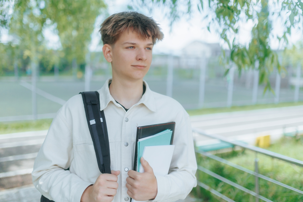 Uczeń klasy maturalnej w białej koszuli trzyma dokumenty