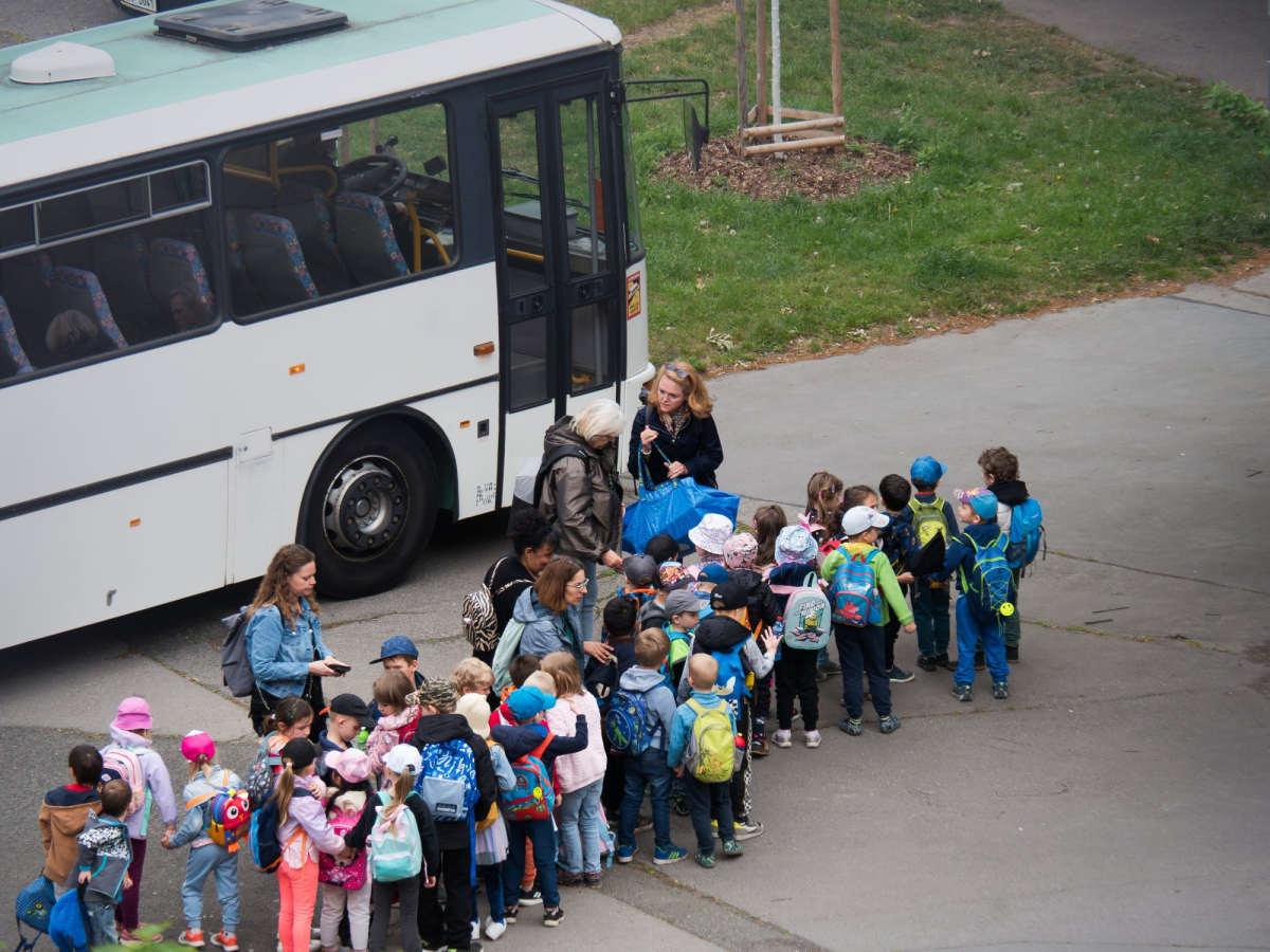 dzieci czekają na wejście do autobusu przy wyjeździe na kolonie