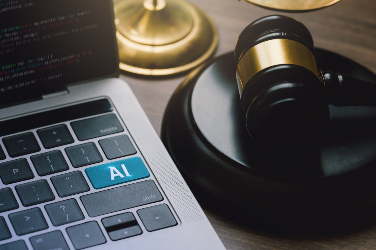 AI zamiast Enter na klawiaturze laptopa, obok na biurkua młotek sędziowski