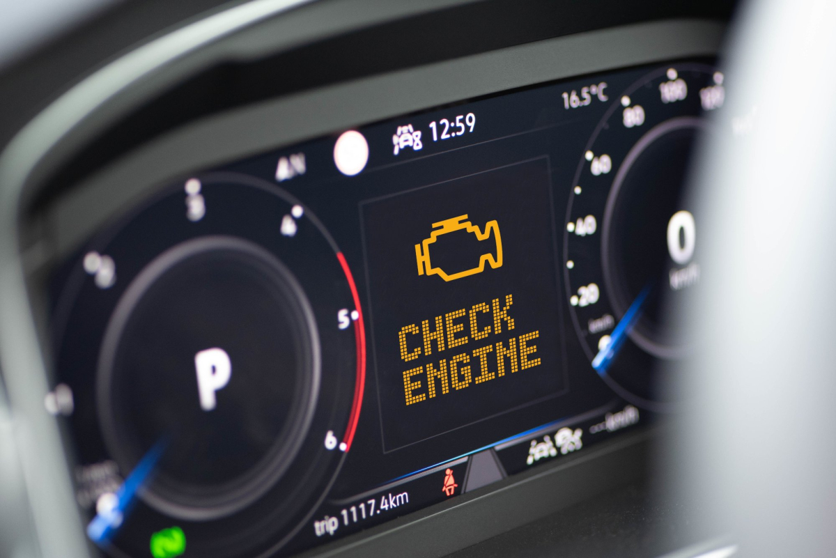 widok na elektroniczne zegary samochodu, duża kontrolka check engine na środku