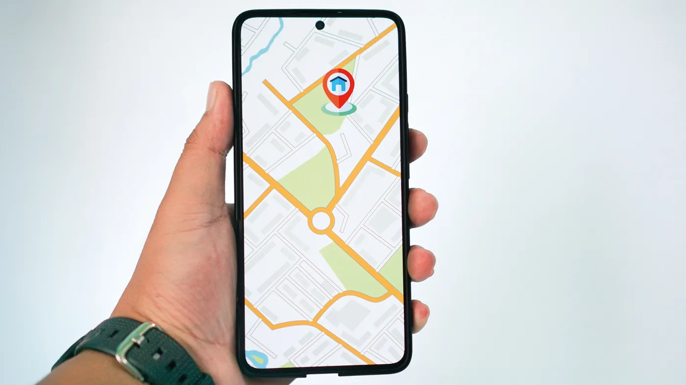 Kupujący mieszkanie, trzymający smartfon z czytelną mapą i pinezką przy budynku