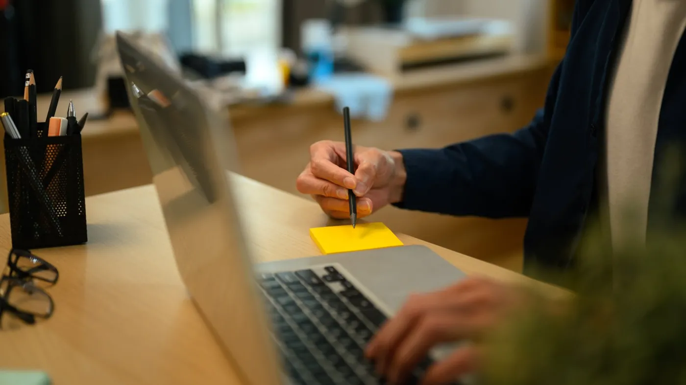 Cropped,Shot,Man,Writing,On,Sticky,Notes,And,Using,Laptop
