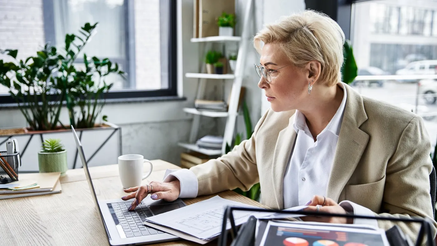 An,Adult,Woman,Dressed,Elegantly,Focuses,On,Her,Laptop,While