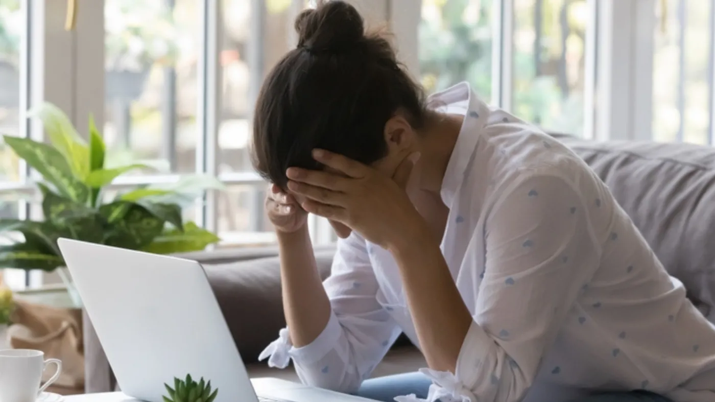 Kobieta załamana pracą, obowiązkami, siedzi przy biurko i laptopie