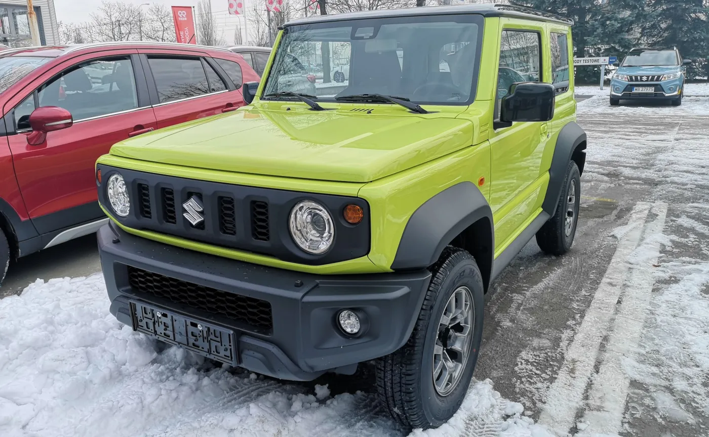 Suzuki Jimny swoją pudełkowatą trzydrzwiową karoserią w energetycznym kolorze kinetic yellow z łatwością wywołuje uśmiech wielkości banana
