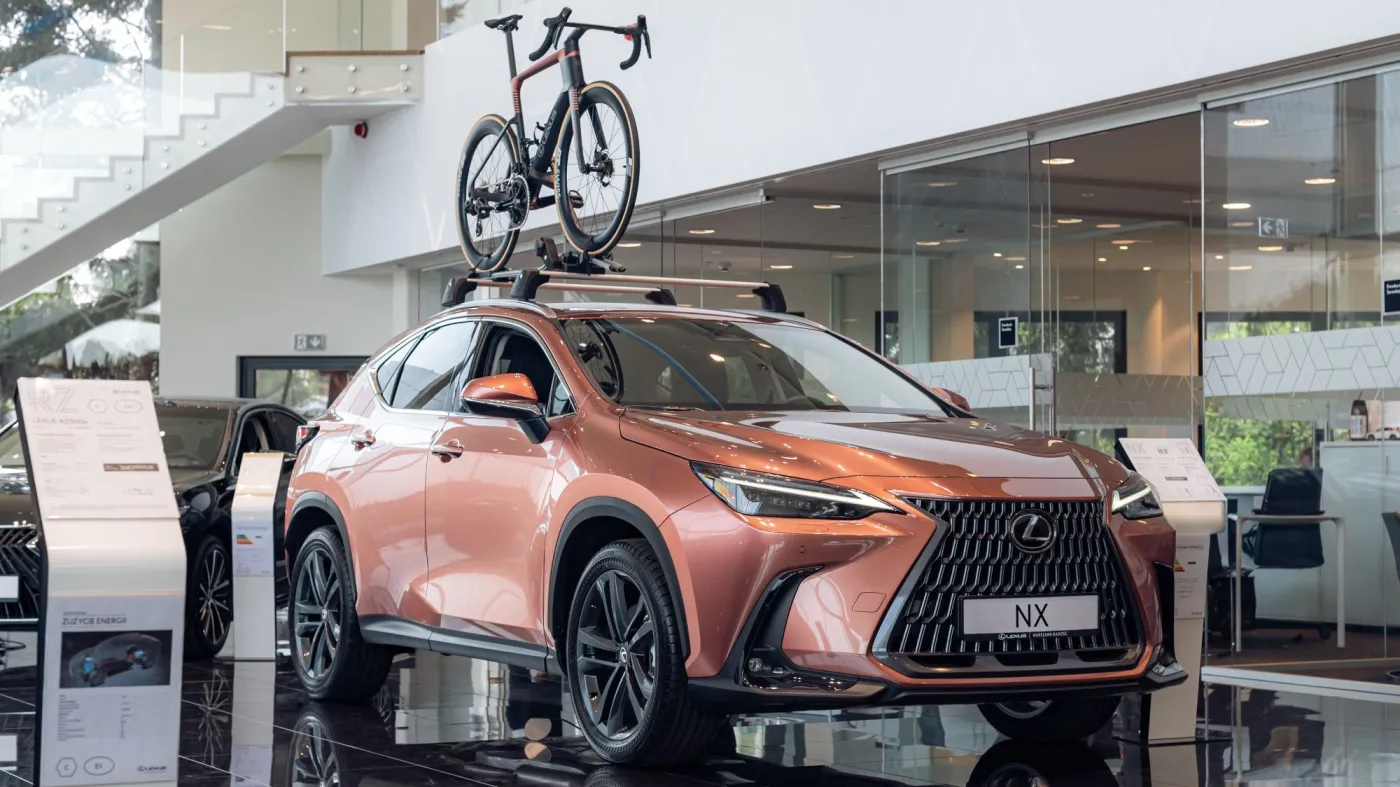 Miedziany Lexus NX w salonie z zamontowanym na bagażniku dachowym szosowym rowerem Lexus Race Bike