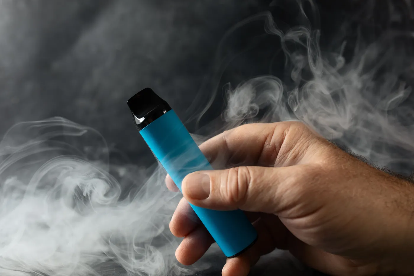 Disposable,Electronic,Cigarette,In,A,Man's,Hand,On,A,Dark