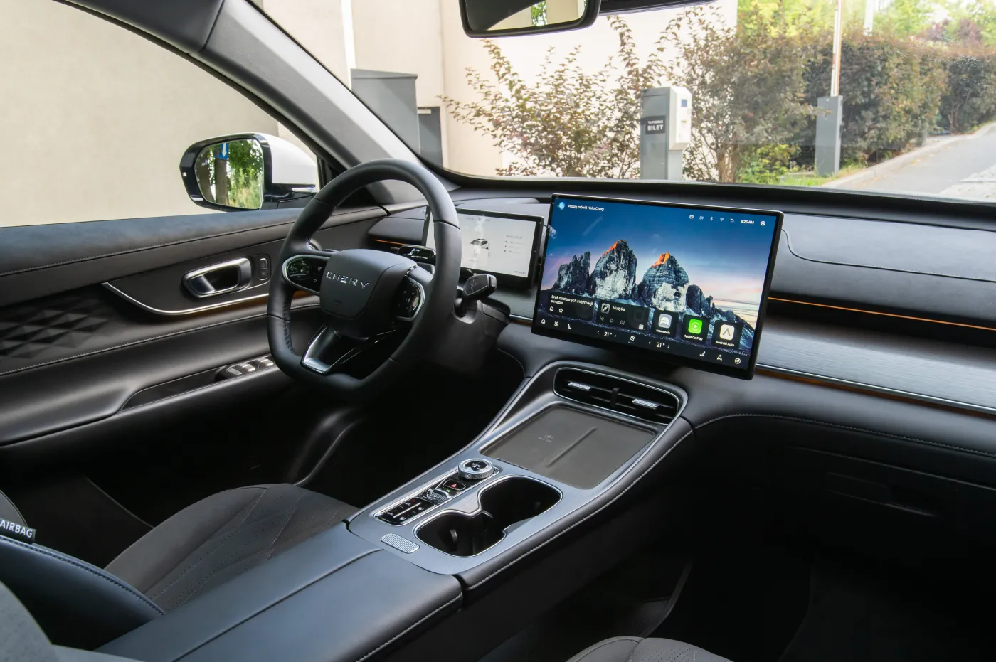 Nowoczesne wnętrze chińskiego samochodu marki Chery Tiggo 8 PHEV z dużym centralnym ekranem multimedialnym i skórzaną kierownicą