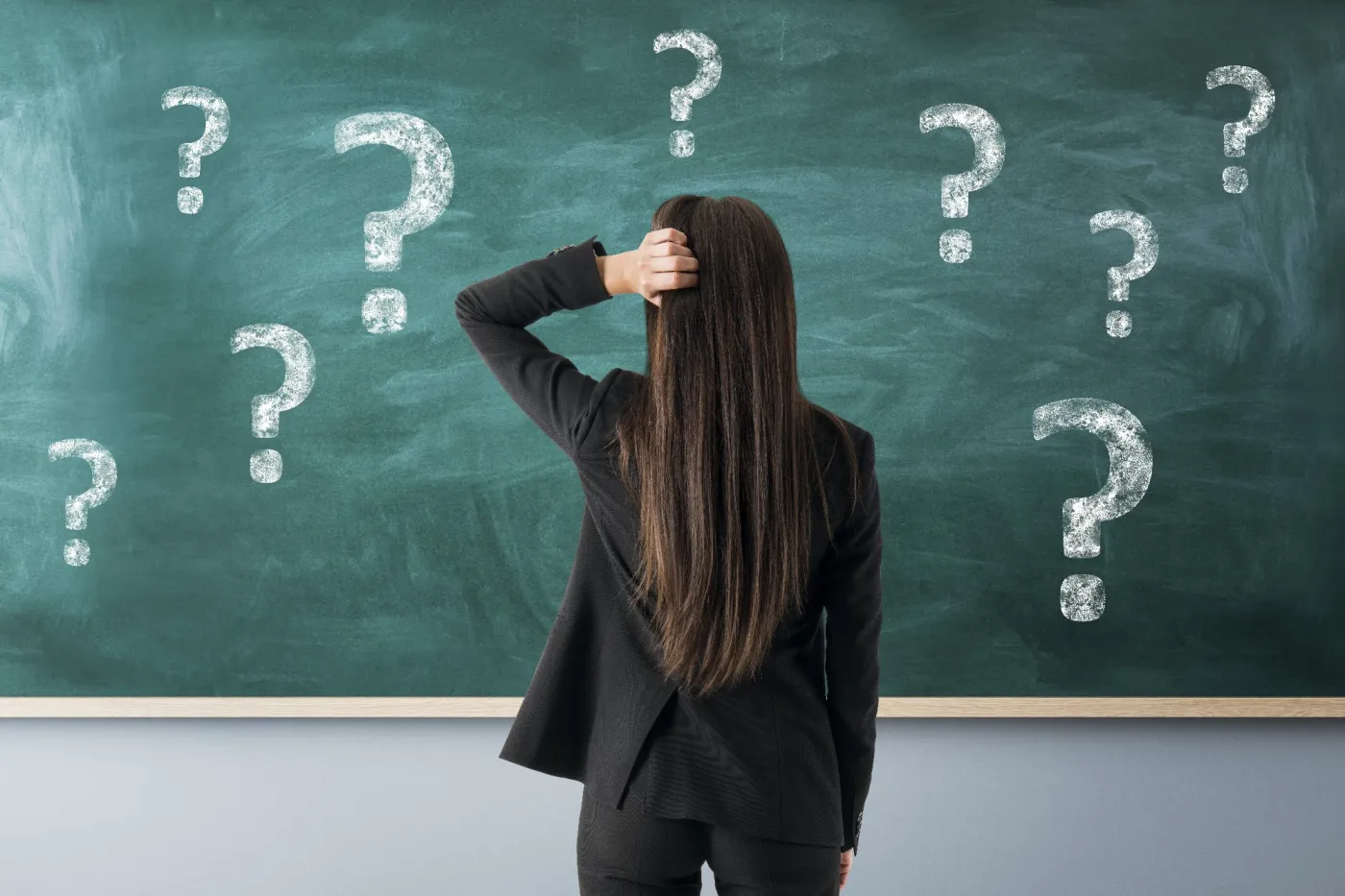 Woman,Seen,From,Behind,Before,Chalkboard,With,Question,Marks,,Realistic