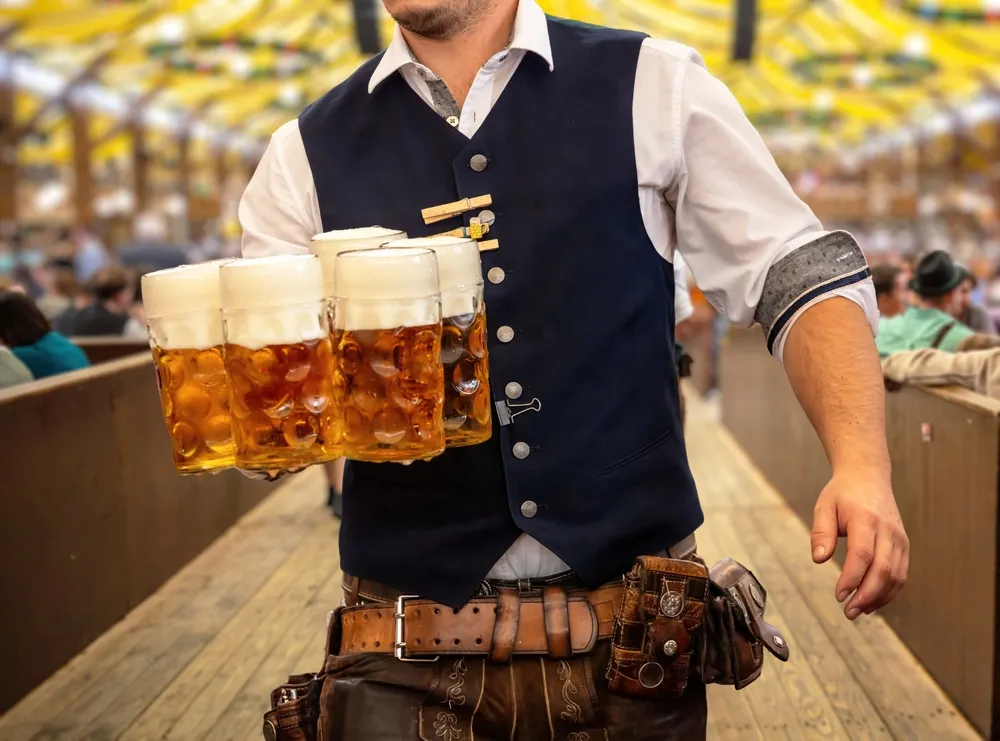 Oktoberfest,,Munich.,Waiter,In,Traditional,Bavarian,Costume,Serving,Beers,,Close