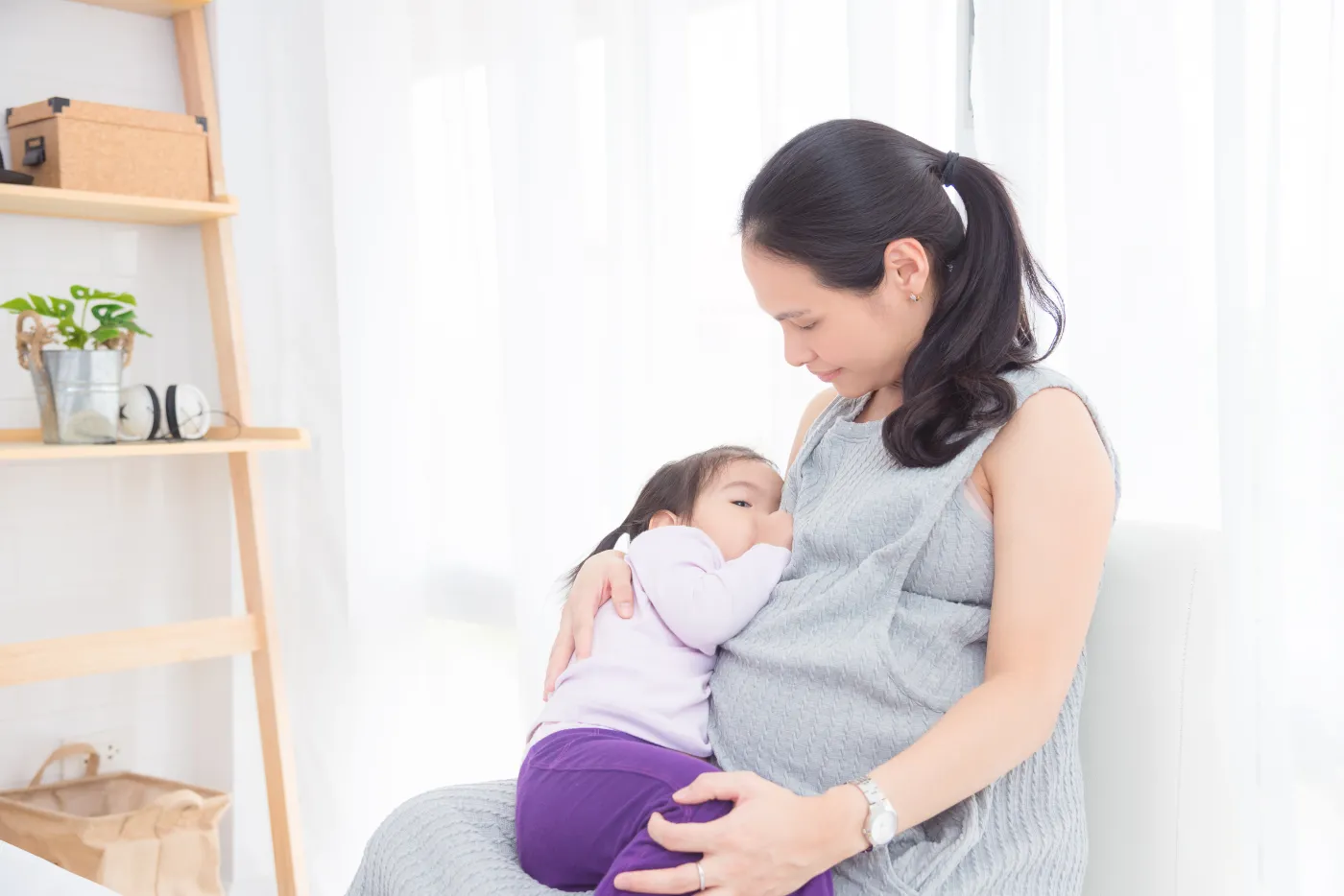 Pregnant,Asian,Mother,Breast,Feeding,Her,Daughter,At,Home