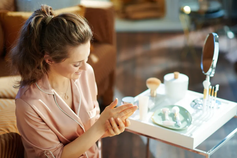 Happy,Modern,Middle,Age,Woman,In,Pajamas,Applying,Hand,Cream