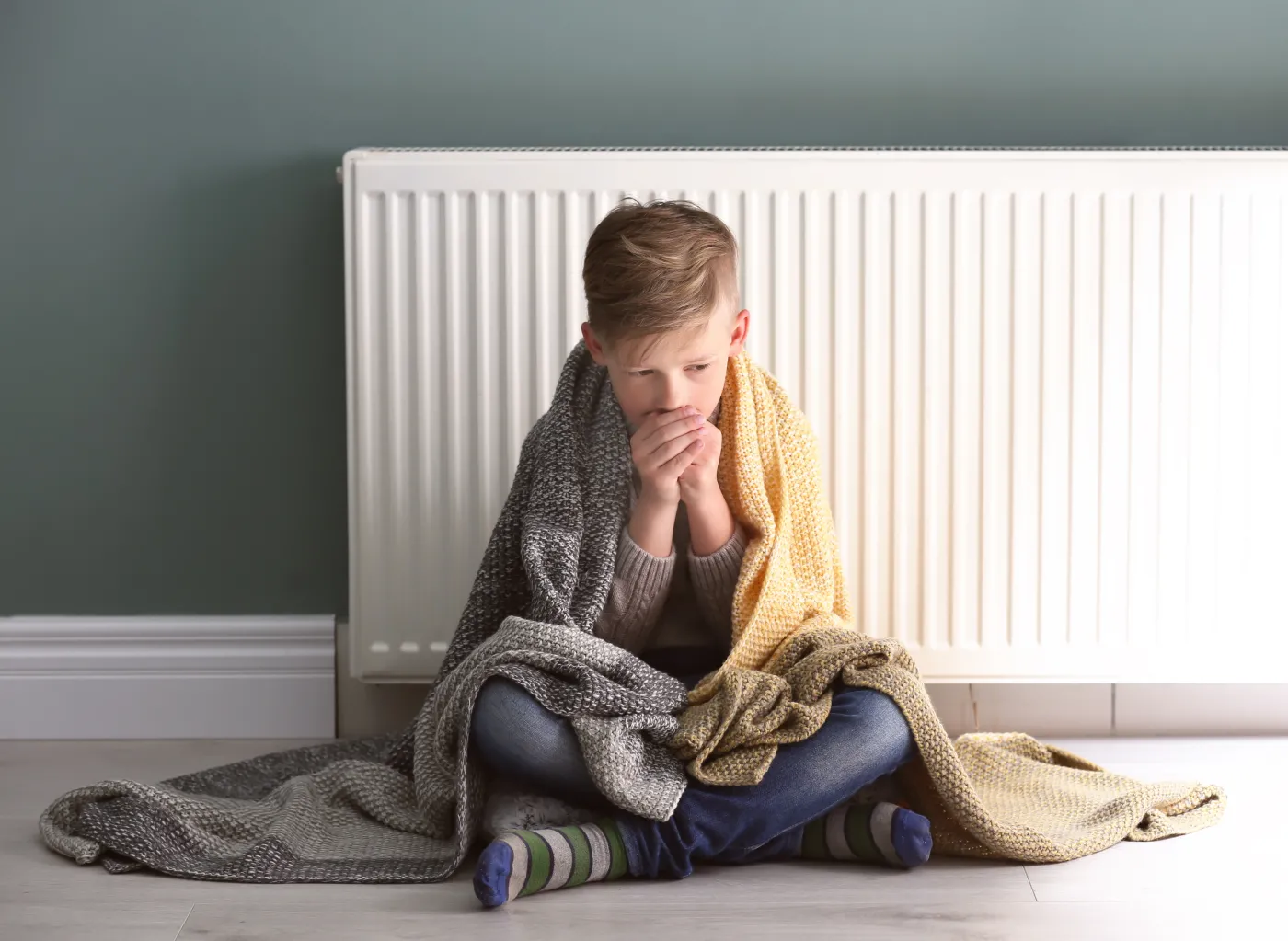 Sad,Little,Boy,Suffering,From,Cold,On,Floor,Near,Radiator
