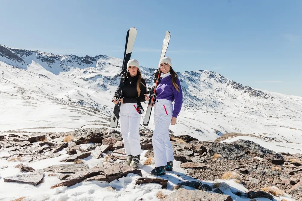 Cheerful,Young,Skier,Women,Standing,On,Top,Of,A,Mountain