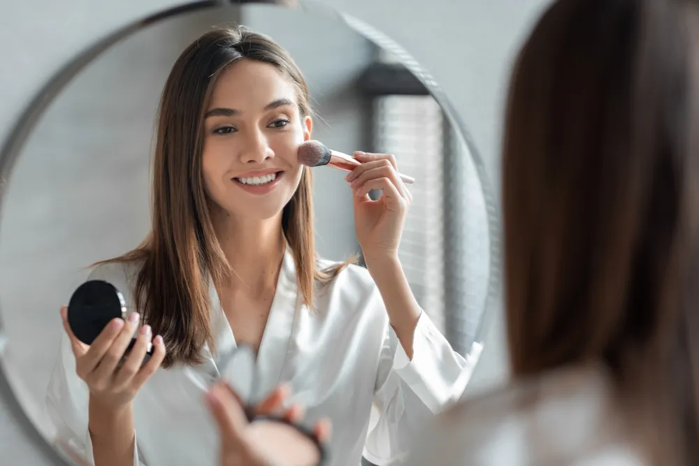 Attractive,Young,Woman,Doing,Daily,Makeup,While,Standing,Near,Mirror