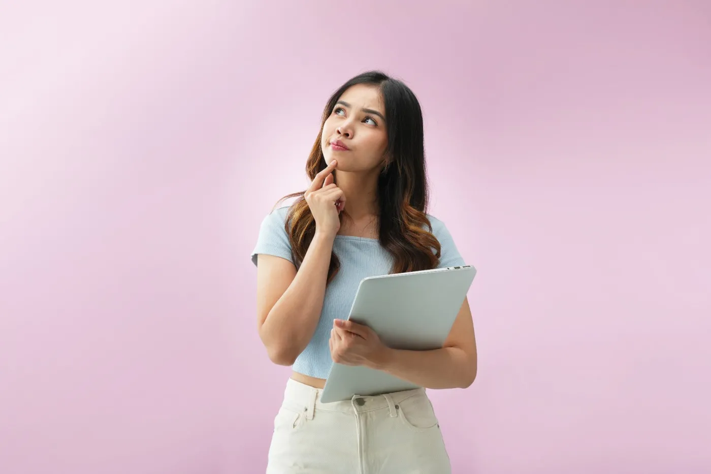 Thoughtful,Young,Asian,Woman,Holding,A,Laptop,And,Looking,Up