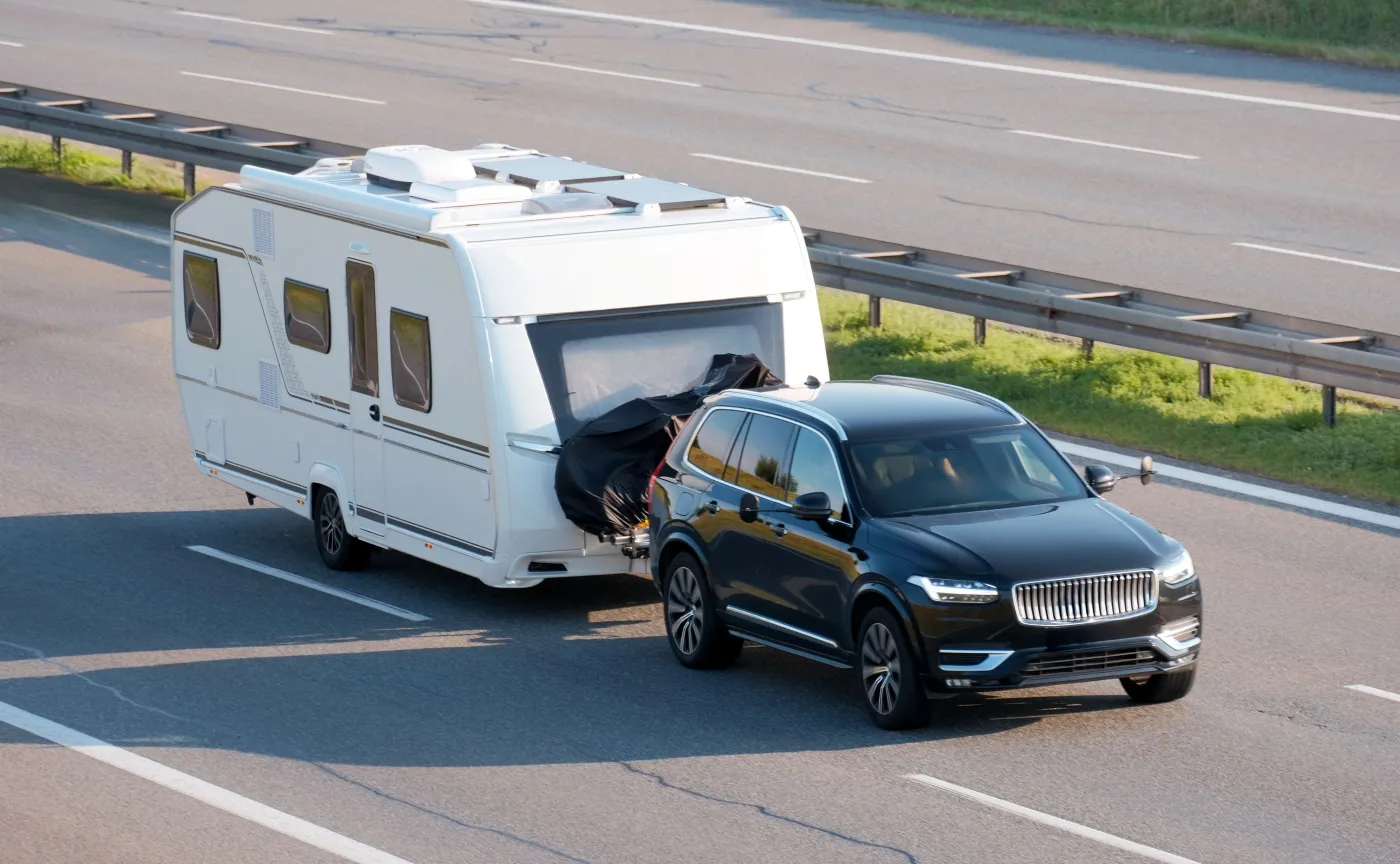 Samochód z białą przyczepą kempingową jedzie po autostradzie