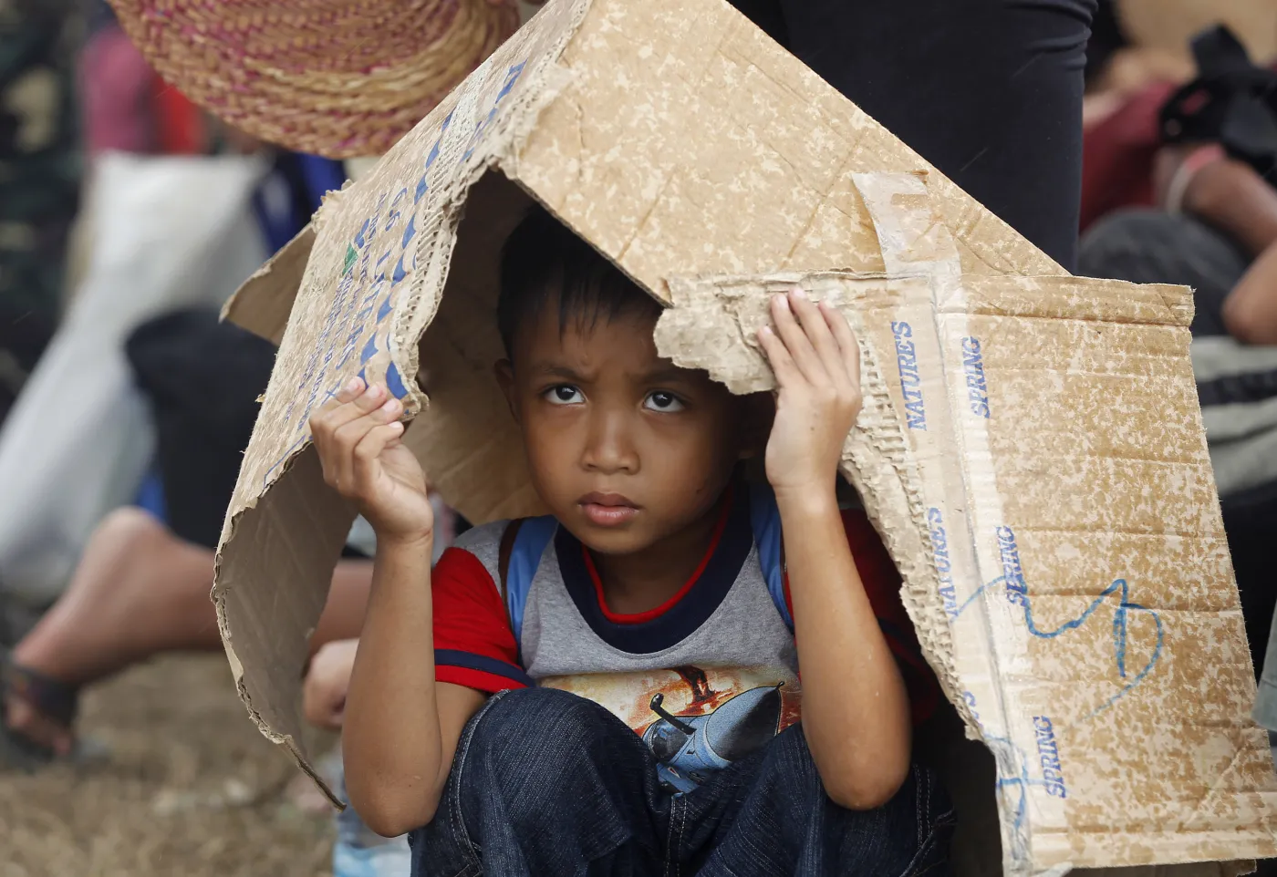 Filipiny po przejściu tajfunu Haiyan. Chłopiec kryje się przed deszczem pod kartonem
