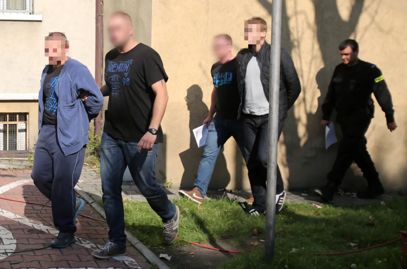 Policjanci wyprowadzają dwóch mężczyzn podejrzanych o podłożenie ładunku pirotechnicznego na stadionie chorzowskiego Ruchu