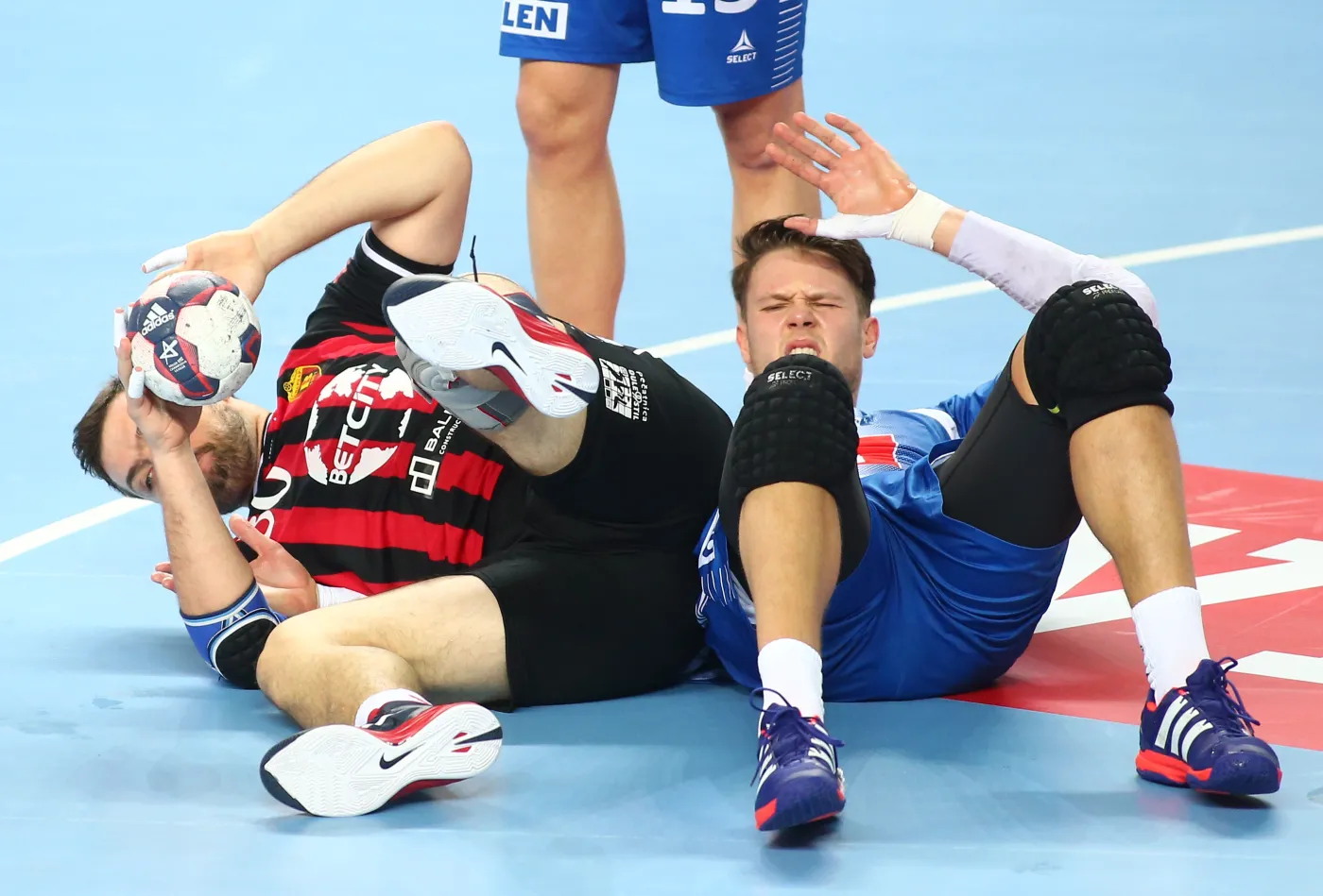Po starciu leżą na parkiecie atakujący Mikhail Chipurin (L) z HC Vardar i blokujący Kamil Syprzak (P) z miejscowej Orlen Wisły w pierwszym meczu 1/8 finału Ligi Mistrzów piłkarzy ręcznych, rozegranym w Płocku