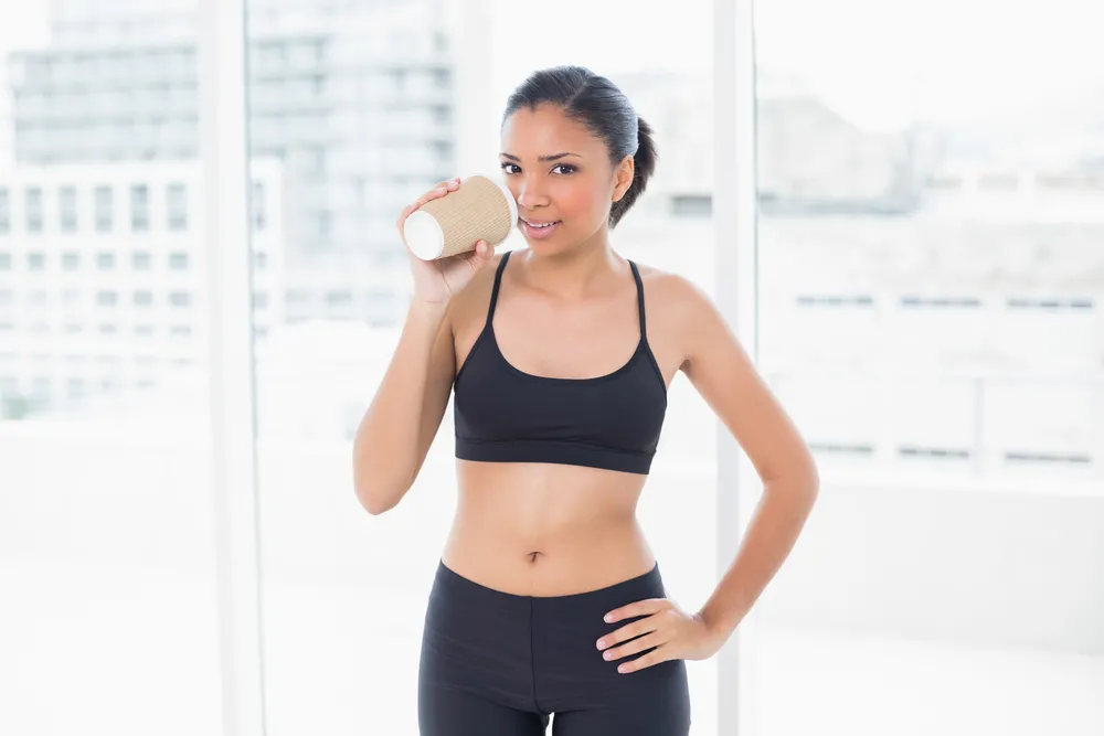 Kobieta pijąca kawę w czasie treningu fitness