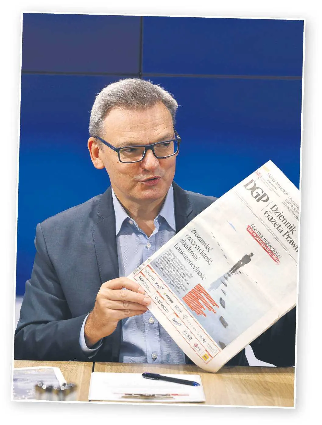 Krzysztof Jedlak - redaktor naczelny Dziennika Gazety Prawnej, pokazuje poprzednią edycję wydania specjalnego DGP