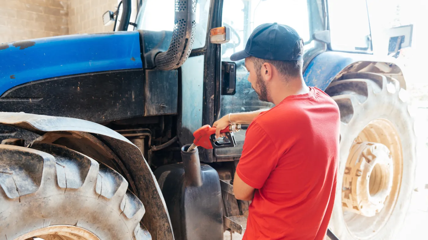 Rolnik stoi przy maszynie, traktorze.