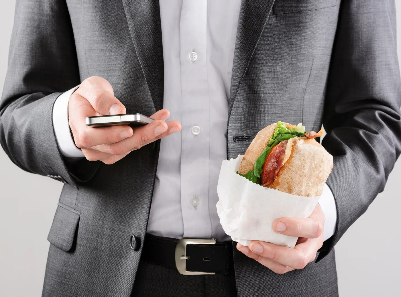 mężczyzna w garniturze je hamburgera