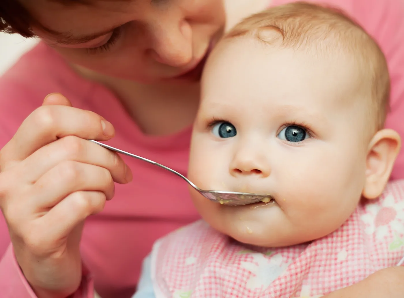 Kobieta karmi niemowlę łyżeczką