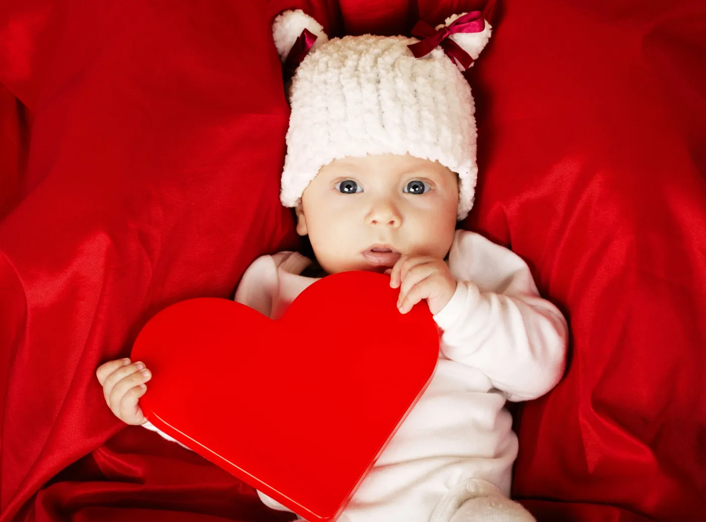 Niemowlę trzyma poduszkę-serce