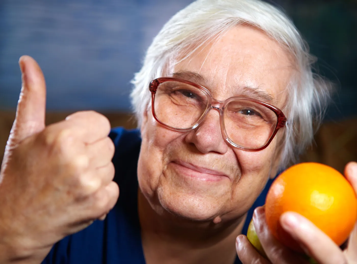 Starsza kobieta trzyma pomarańczę