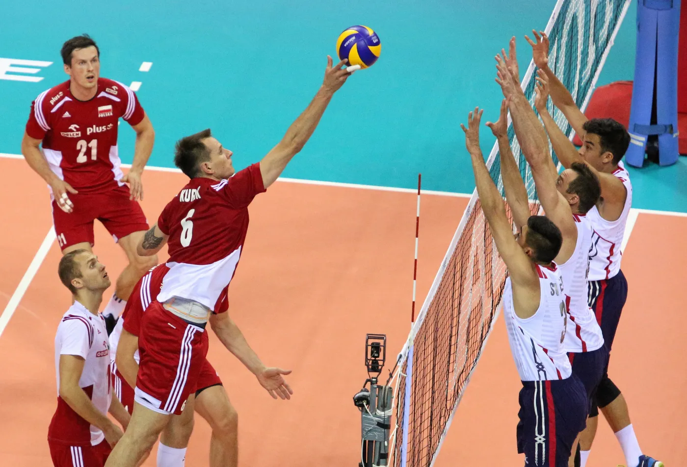 Reprezentant Polski Bartosz Kurek (L) przebija piłkę nad blokiem drużyny USA: Taylor Sander, David Lee (C-P) i Kawika Shoji (P) podczas meczu Ligi Światowej siatkarzy, Polska - USA, rozegranego w Tauron Arenie Kraków