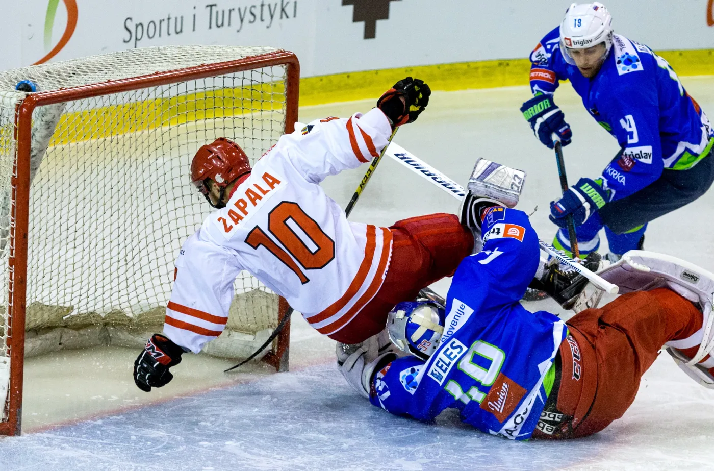 Polak Krzysztof Zapała (L) wpada na bramkarza Słowenii Lukę Gracnara (C) podczas meczu hokejowego turnieju EIHC w Katowicach