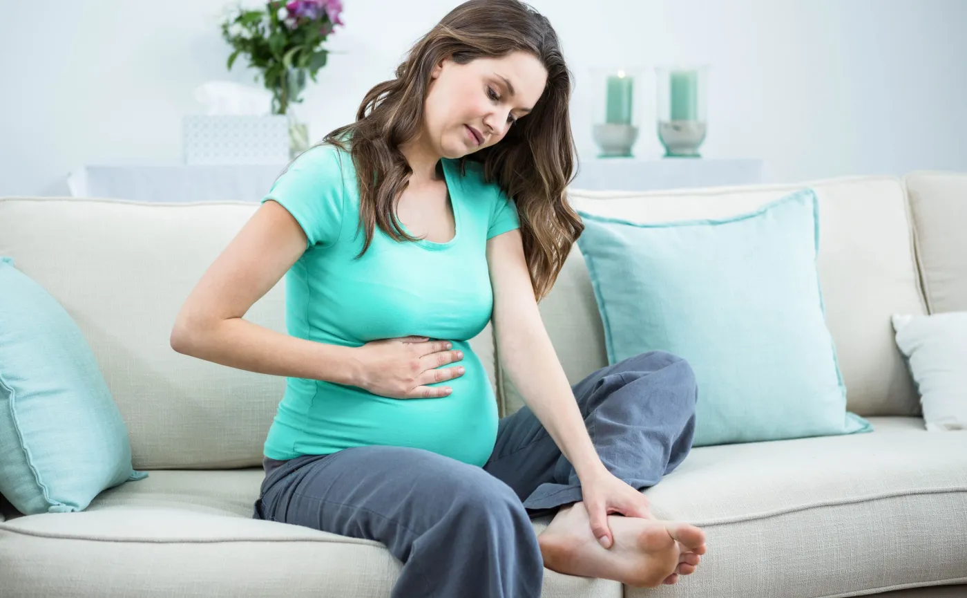 Kobieta w ciąży masuje stopę