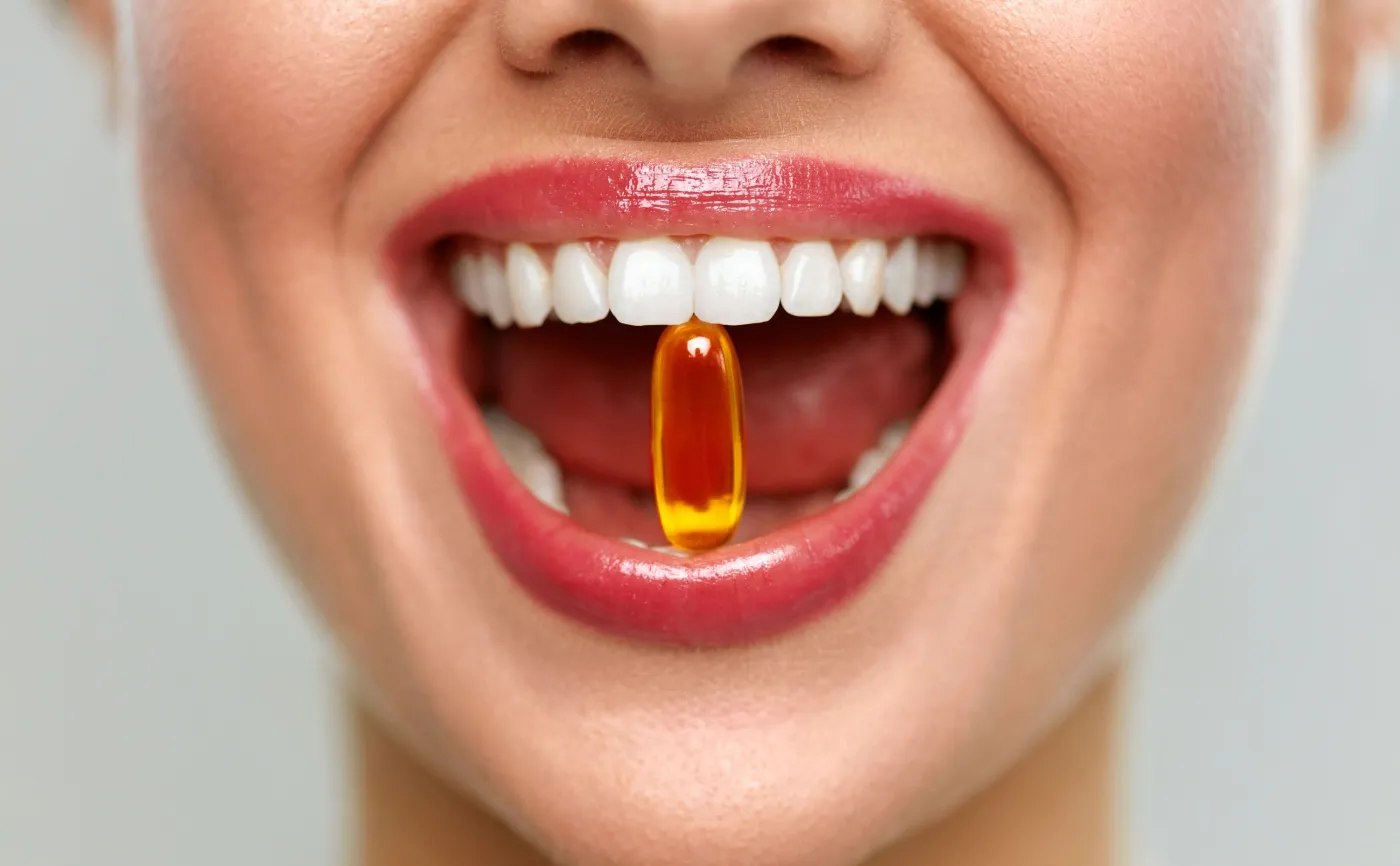 Kobieta trzyma w zębach kapsułkę