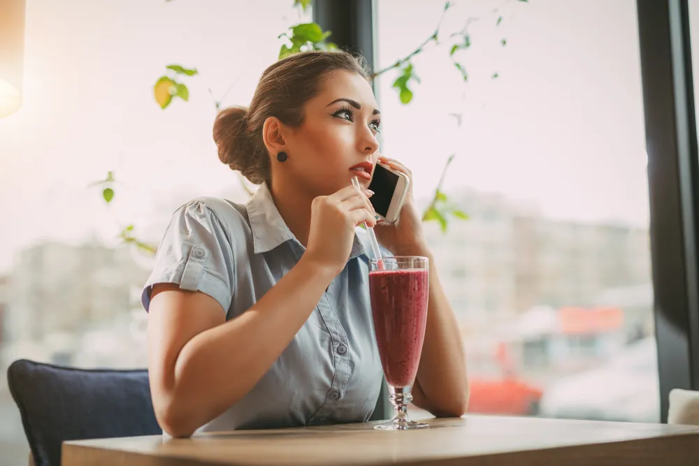 Kobieta pije kolorowe smoothie