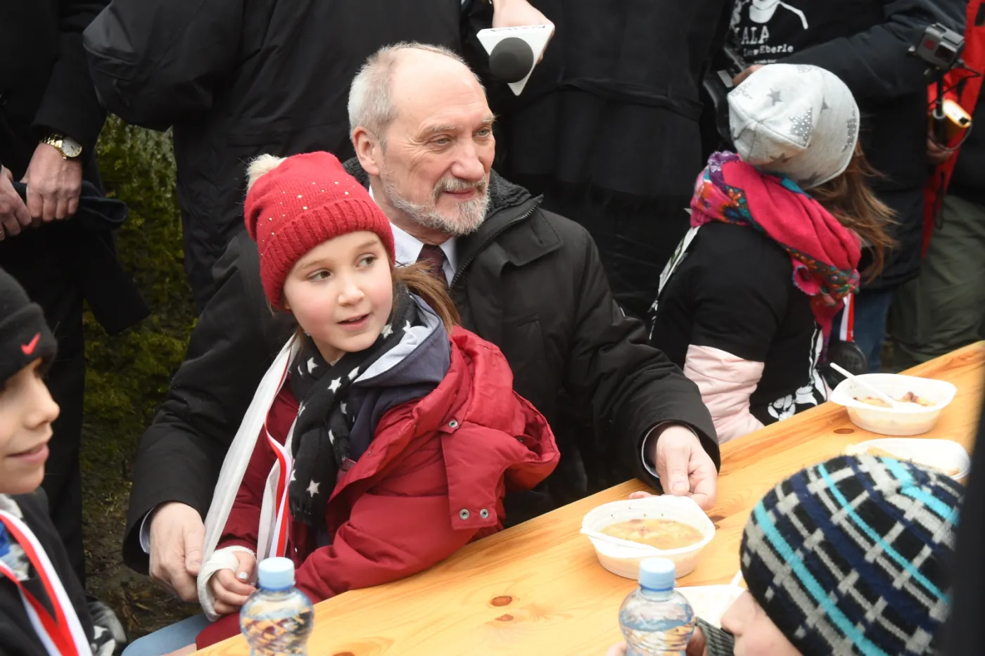 Minister obrony narodowej Antoni Macierewicz siedzi przy stole z najmłodszymi uczestnikami biegu - dla wszystkich chętnych kuchnia polowa przygotowała gorącą grochówkę.
