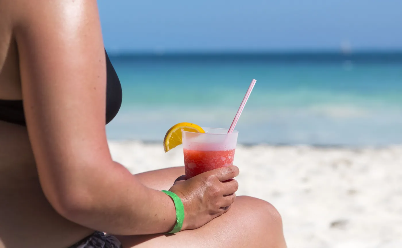 Kobieta na plaży pije zimny napój