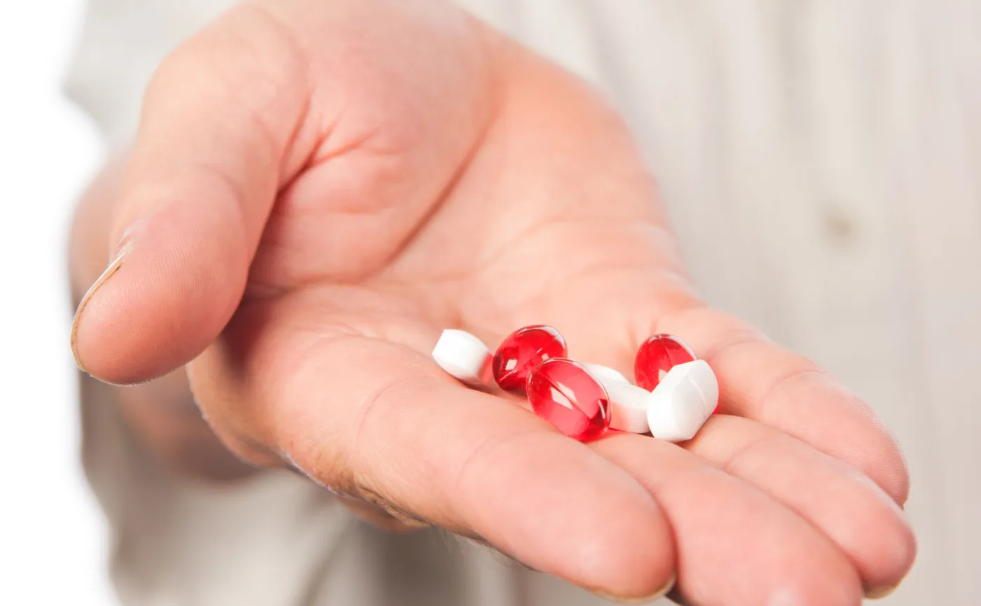 Mężczyzna trzyma w dłoni pigułki
