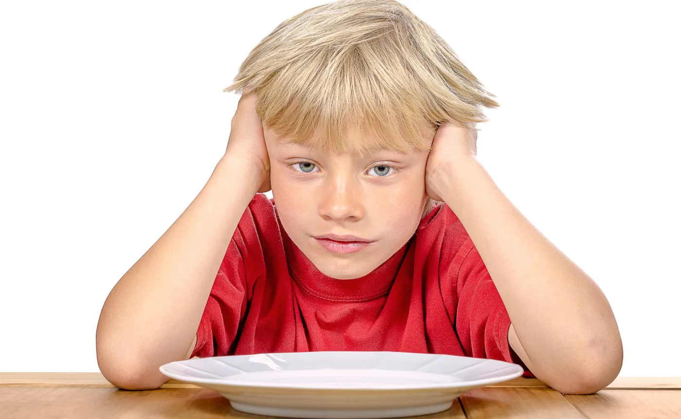 Dziecko siedzi nad pustym talerzem
