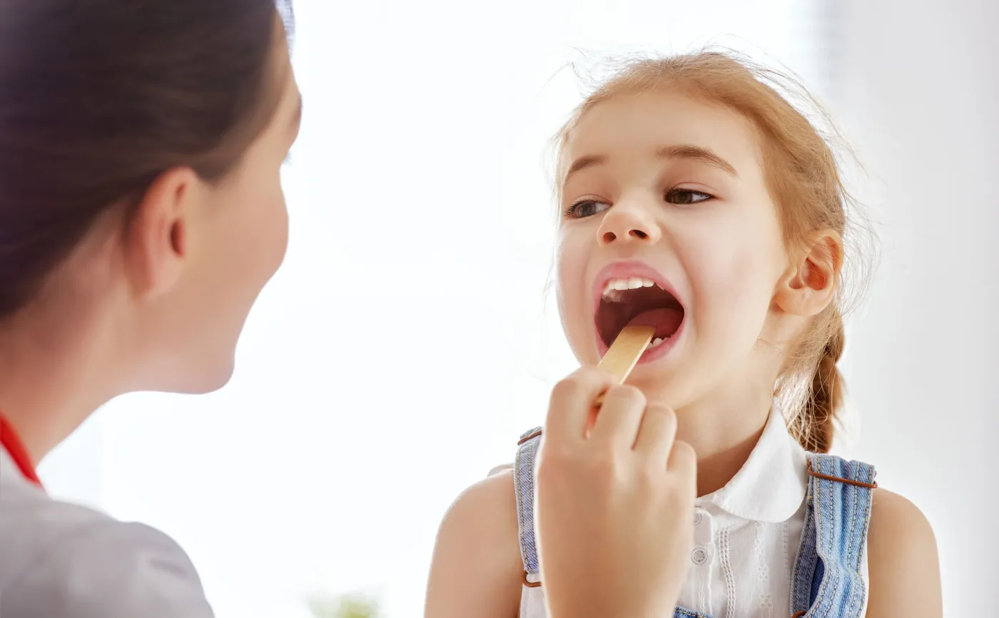 Lekarz zagląda do gardła dziecka