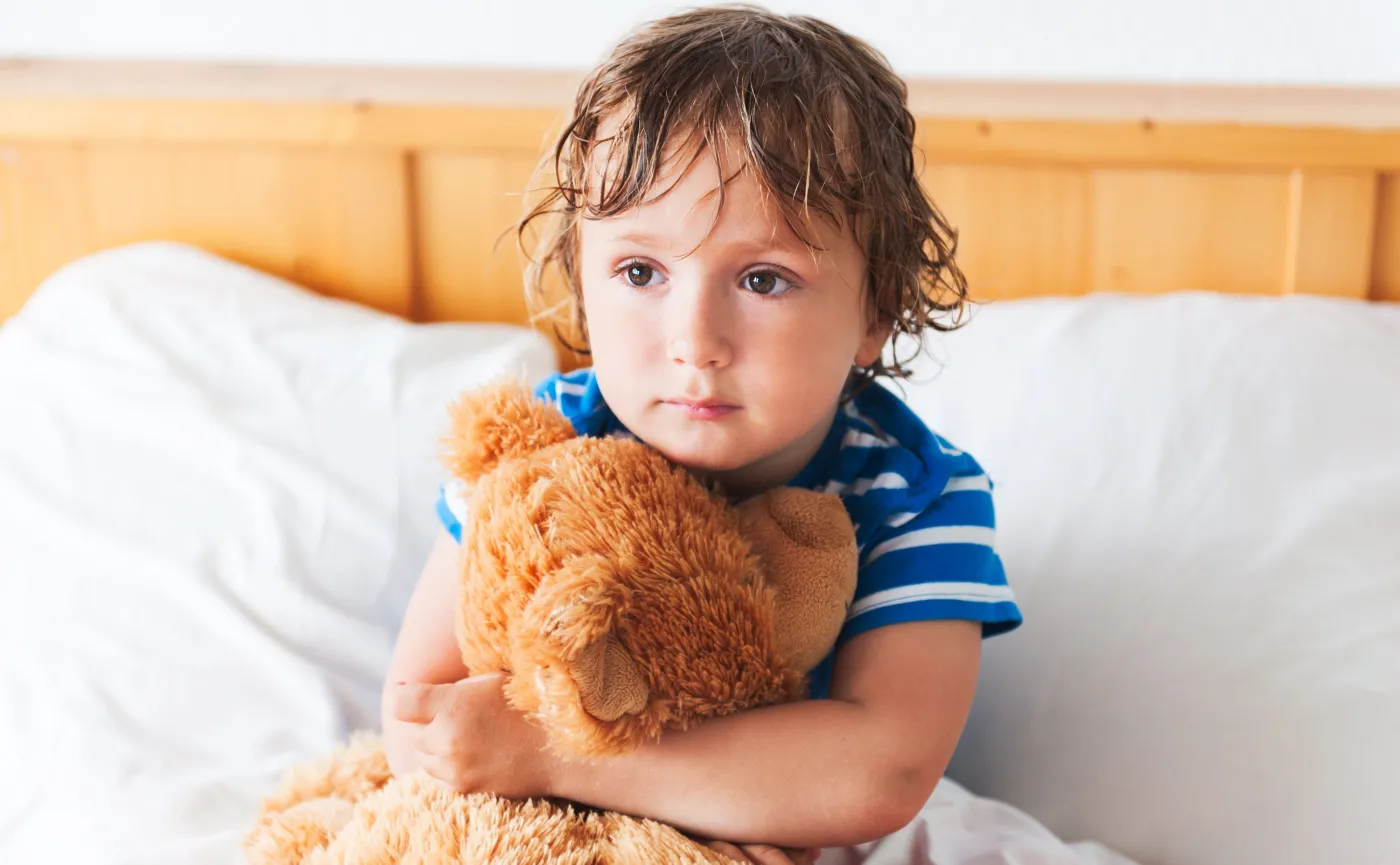 Smutne dziecko siedzi w łóżku
