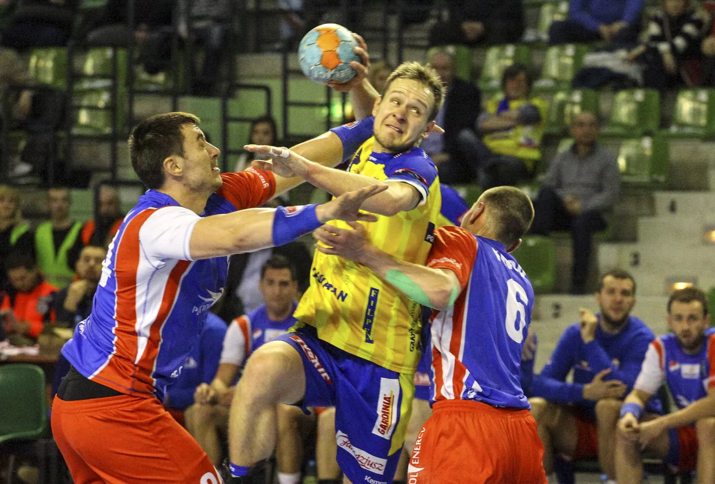 Zawodnik Vive Targi Kielce Mateusz Jachlewski (C) blokowany przez Jakuba Płócienniczaka (L) i Wojciecha Knopa (P) z Gwardii Opole