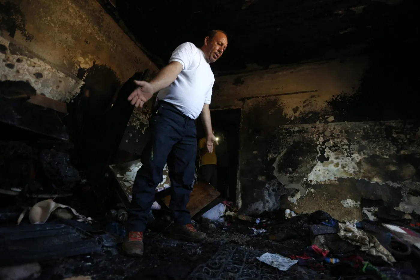 Mężczyzna na miejscu palestyńskiego domu spalonego przez żydowskich osadników, Nablus, Zachodni Brzeg Jordanu