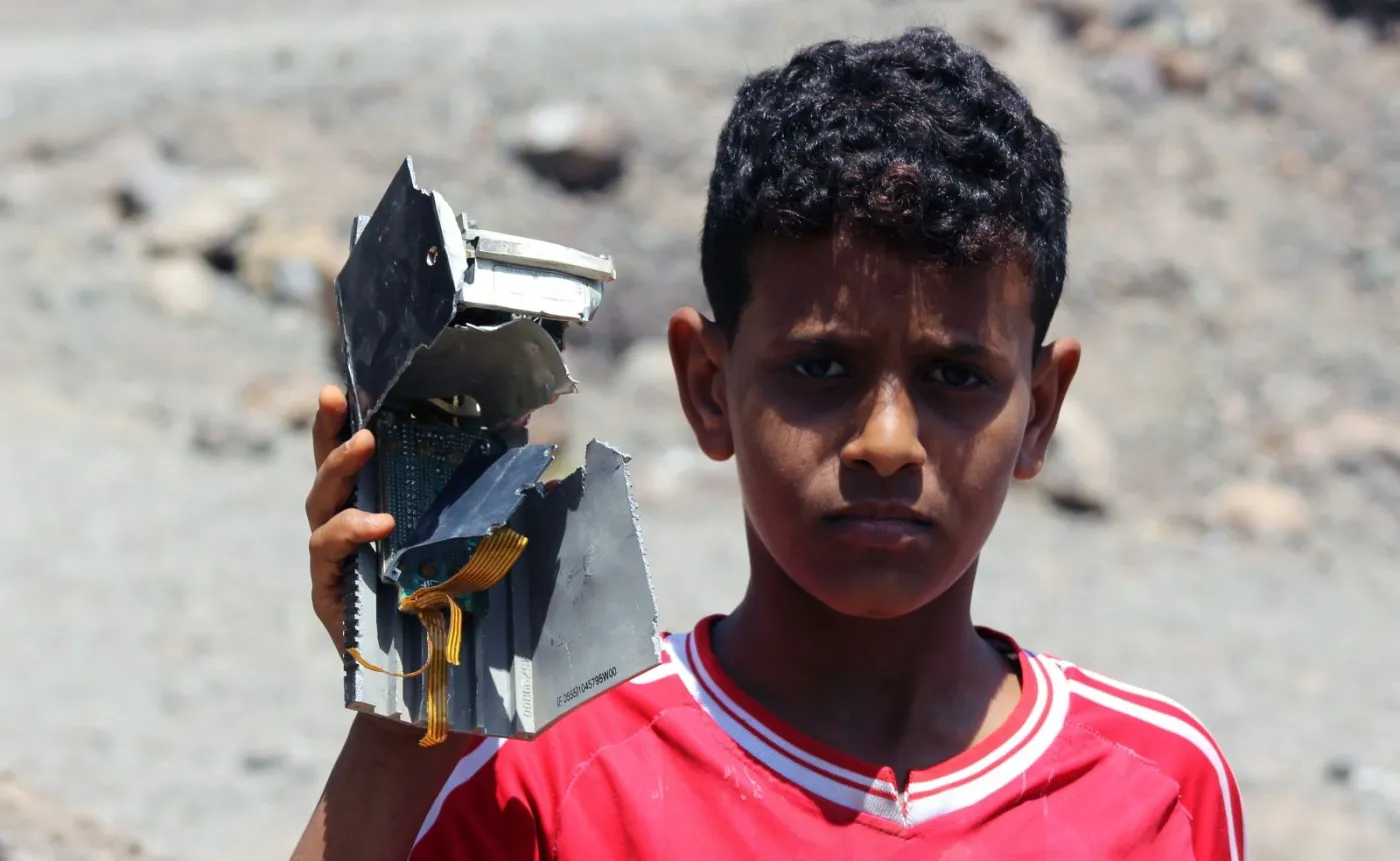 Jemen. Chłopiec prezentuje kawałek rozbitego samolotu sił koalicji dowodzonej przez Arabię Saudyjską